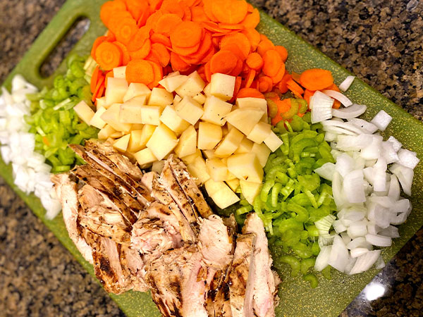 Chopped carrots, chicken, potatoes, onion, and other ingredients for Chicken Pot Pie Soup.