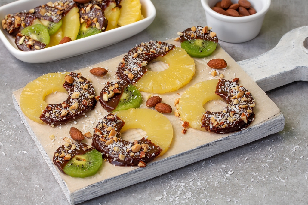 Chocolate-covered pineapple and kiwi with nuts and almonds sprinkled