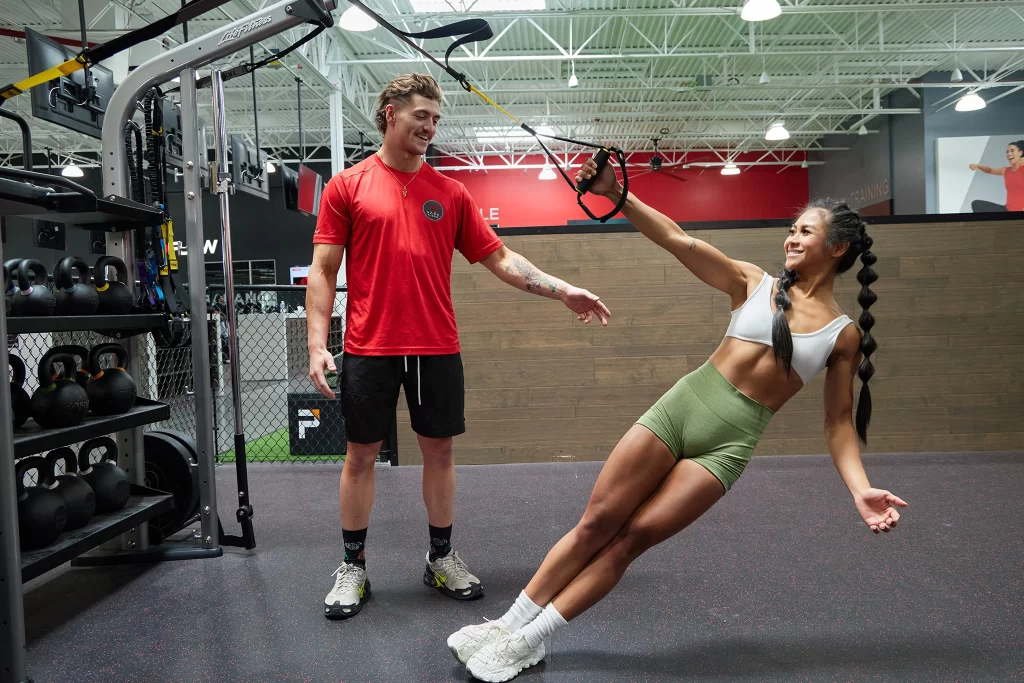 Female athlete working with a personal trainer on TRX bands at VASA Fitness