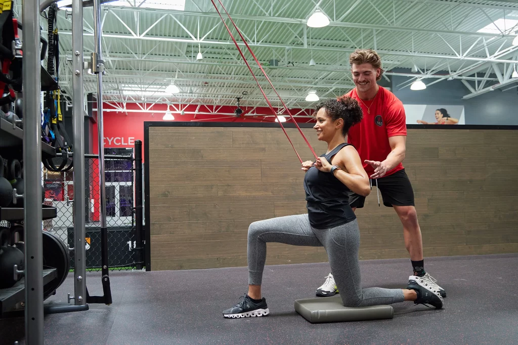 Female athlete working with a male personal trainer with TRX bands at VASA Fintess