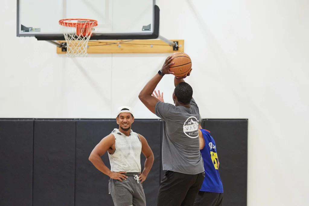 A group of male athletes playing basketball on an indoor court at VASA Fitness